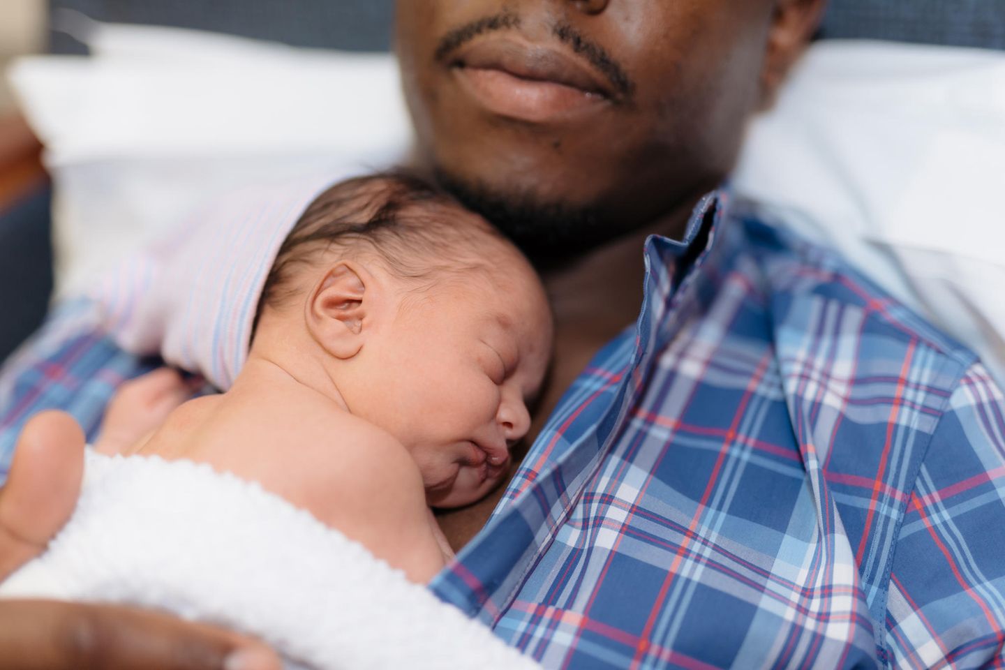 Familienwerdung: ein Vater hat seinen neugeborenen Sohn auf der Brust liegen