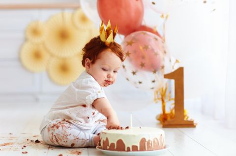 Erster Geburtstag: ein kleiner Jung steckt seine Hand in einen Geburtstagskuchen