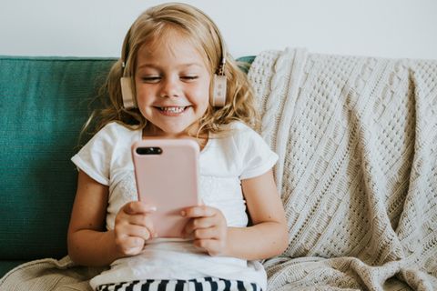 Kinderkopfhörer-Test: Mädchen mit Kinderkopfhörer guckt Video auf Smartphone