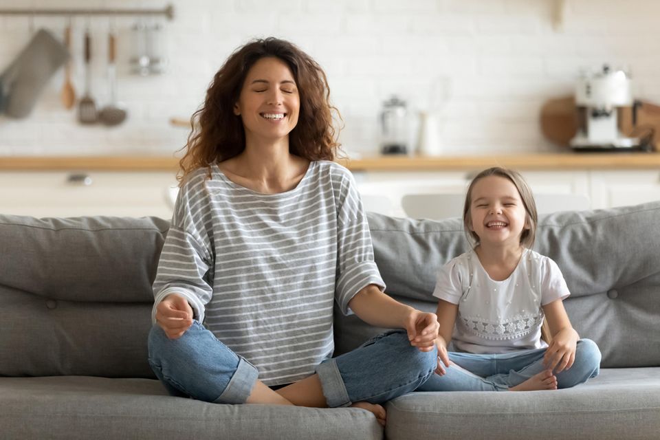 Zuhören lernen: Mutter und ihre kleine Tochter sitzen auf dem Sofa und meditieren