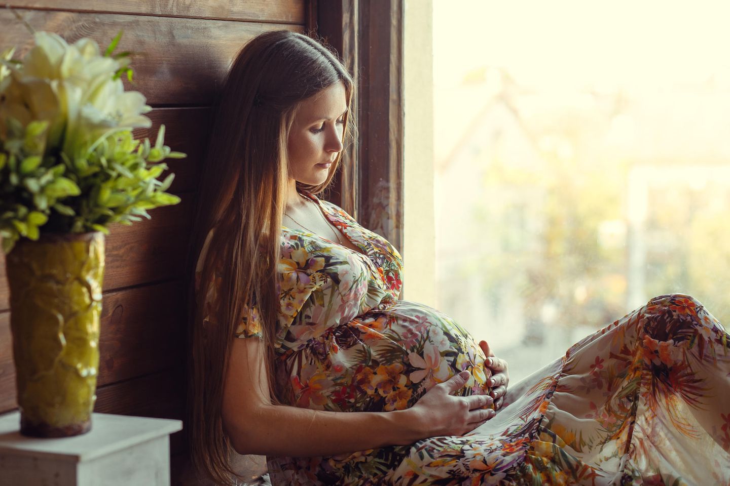 Verändertes Gehirn: eine schwangere Frau mit langen braunen Haaren sitzt vor einem Fenster