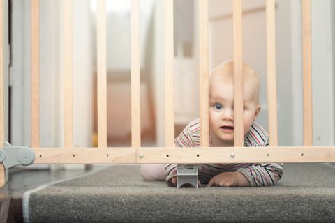 Treppenschutzgitter im Test: Robbendes Baby schaut durch Gitter vor der Treppe.