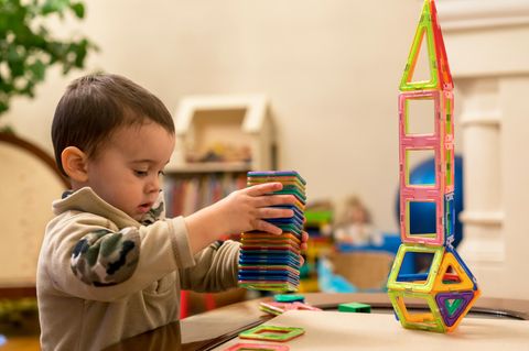 Magnetspielzeug für Kinder: Kleiner Junge baut aus Magnetspielzeug einen Turm.