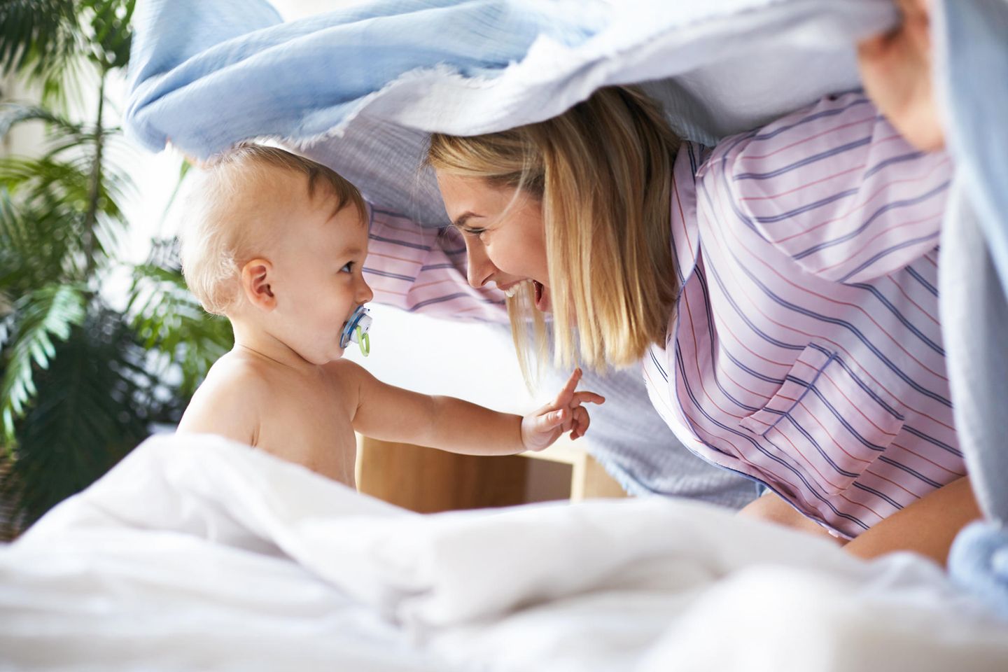 Ein Baby und seine Mama spielen unter der Decke
