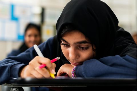 Melisa Erkurt: ein junges Mädchen mit schwarzem Kopftuch sitzt in der Schule