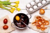 Eier färben mit Zwiebelschalen: Ein Topf mit Zwiebelschalen und einem Ei