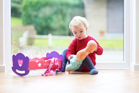 Aufklärung:  ein kleines blondes Mädchen spielt mit ihrer Puppe auf dem Boden