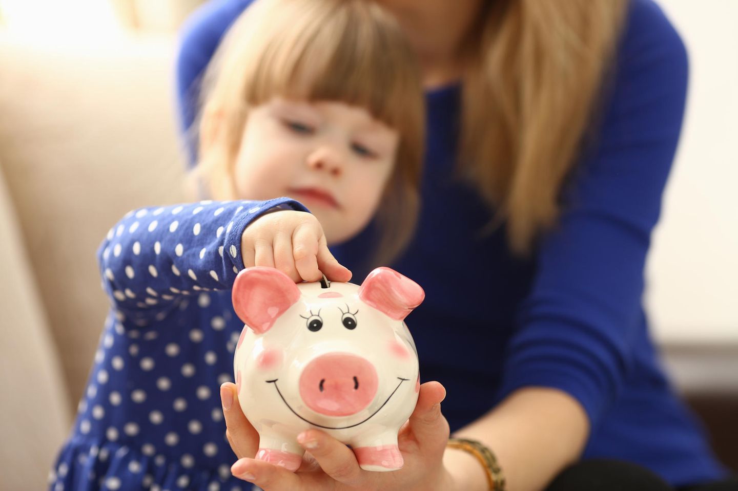 Rechtsfragen für Patchwork-Familien: ein kleines Mädchen steckt eine Münze in ein Sparschwein