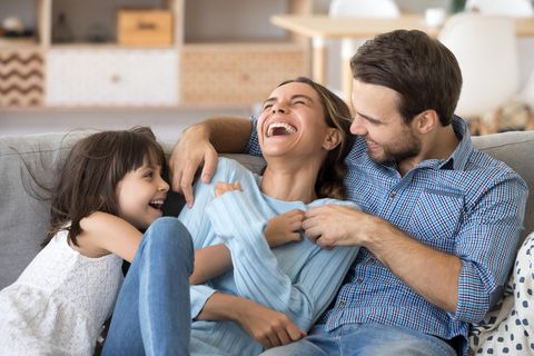 Wetten: Eine Familie lacht, während sie auf dem Sofa sitzen.