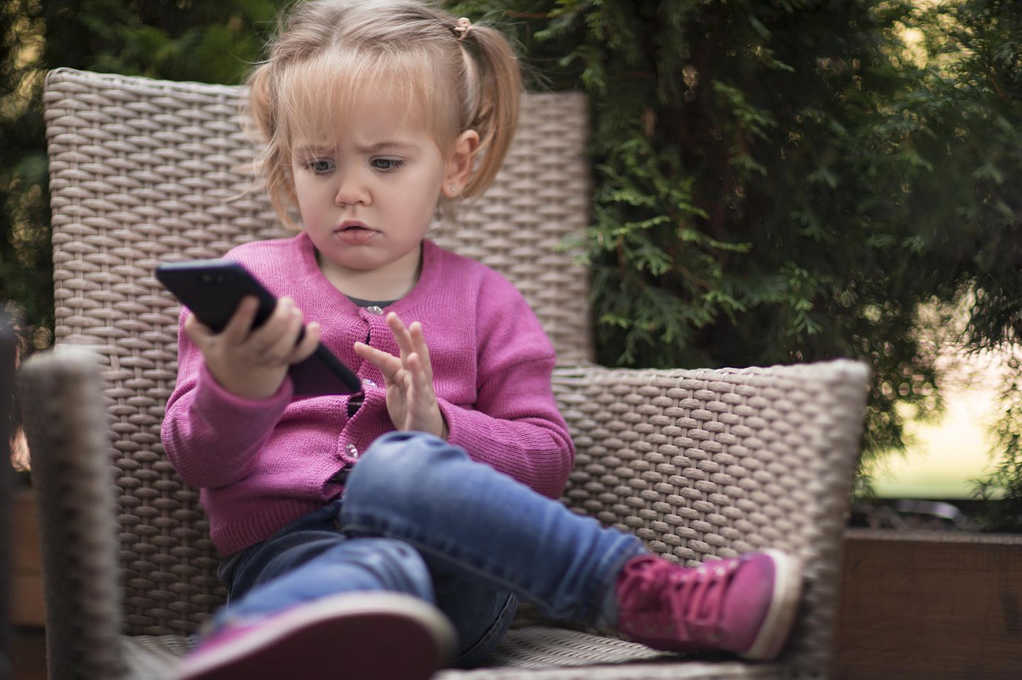 Eltern erzählen: Ein Kind hält ein Handy in der Hand.