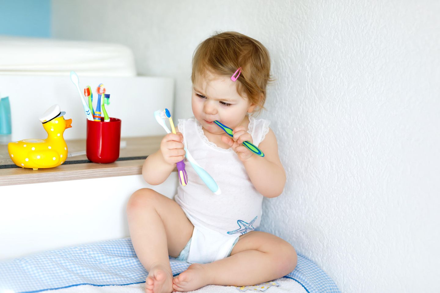 Eltern erzählen: Kind hält mehrere Zahnbürsten in den Händen.