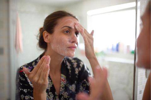 Schnell und gründlich abschminken: Frau reinigt ihr Gesicht vor dem Spiegel