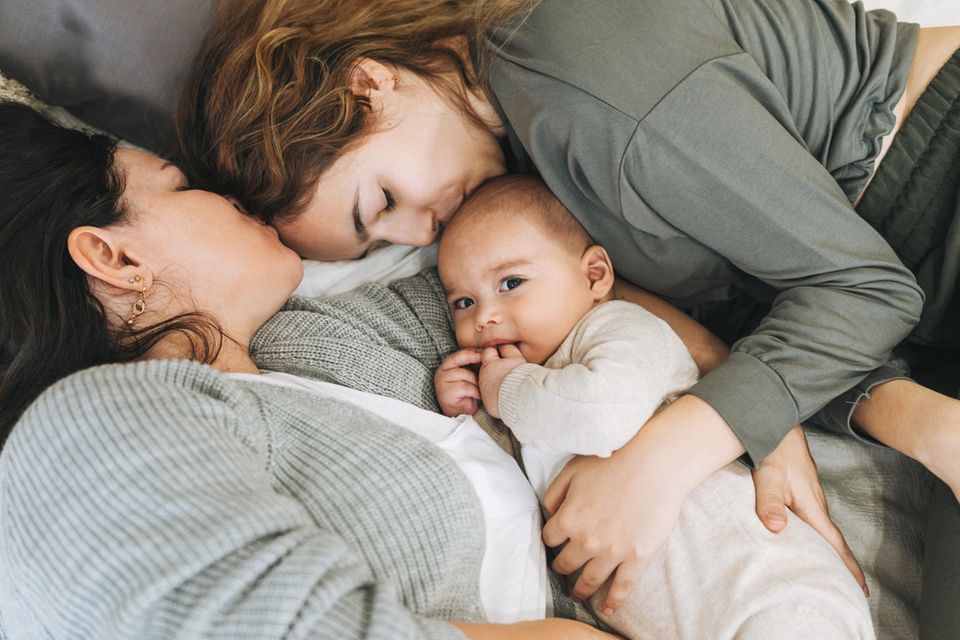 Schöne Haut trotz Schlafmangel: Paar mit Baby im Bett