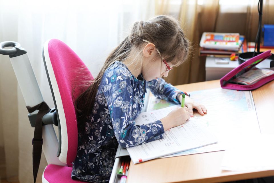Schreibtischstuhl für Kinder im Test: Mädchen macht Schulaufgaben am Schreibtisch.