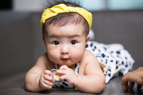 Süßes asiatisches Baby mit Schnuller in der Hand