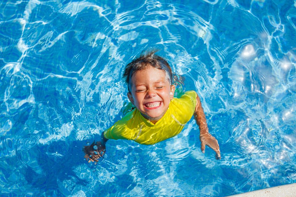 Sicher im Sommer: Kind spielt in neongelben Schwimmsachen im Pool