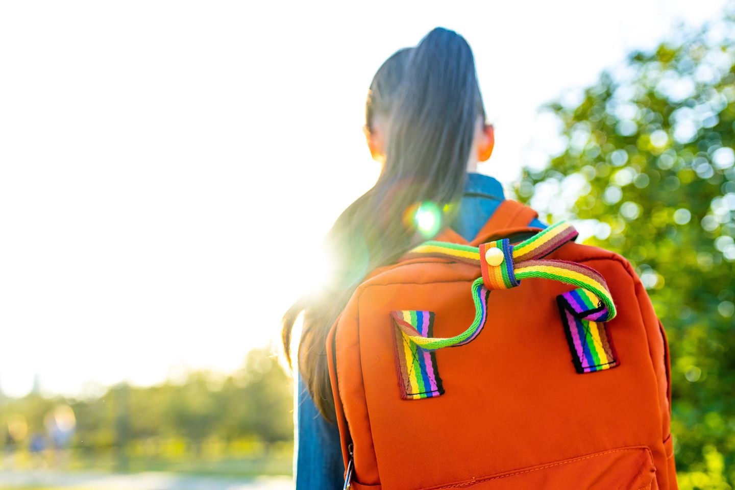Kind mit Regenbogenrucksack geht in die Schule
