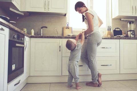 Carearbeit: eine Mutter mit Kind steht in einer Küche an der Arbeitsfläche