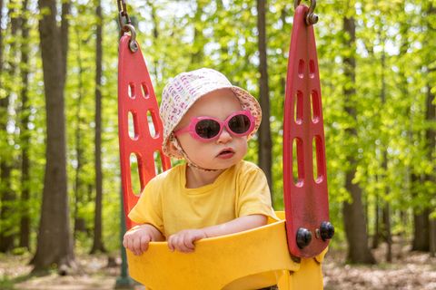 Babysonnenbrillen-Test: Baby sitzt mit Sonnenbrille in Schaukel.
