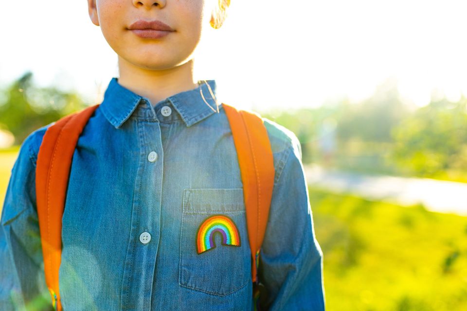 Queere Aufklärung: Kind läuft mit Regenbogen-Aufnäher und Rucksack