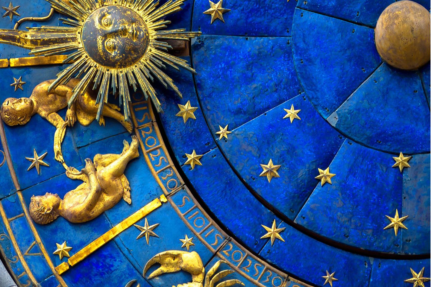 Aszendent Zwilling: Goldenes Symbol des Sternzeichen Zwillings an einer antiken, blauen Uhr