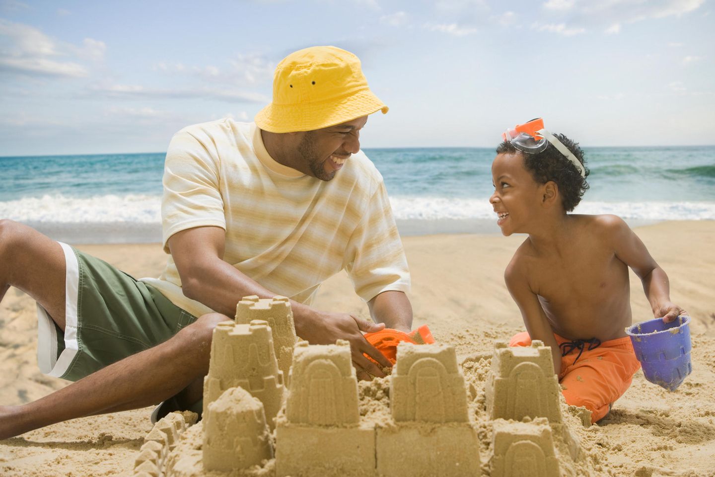 Familienzeit: Vater baut mit seinem Sohn eine Sandburg