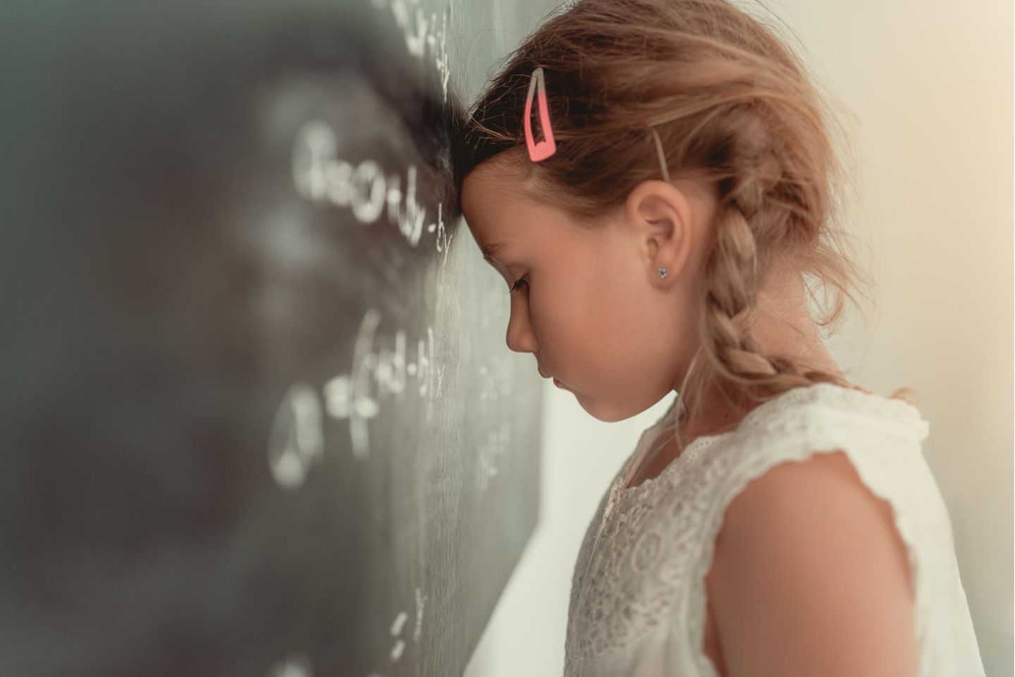 Stress bei Kindern: Mädchen lehnt Kopf gegen die Tafel