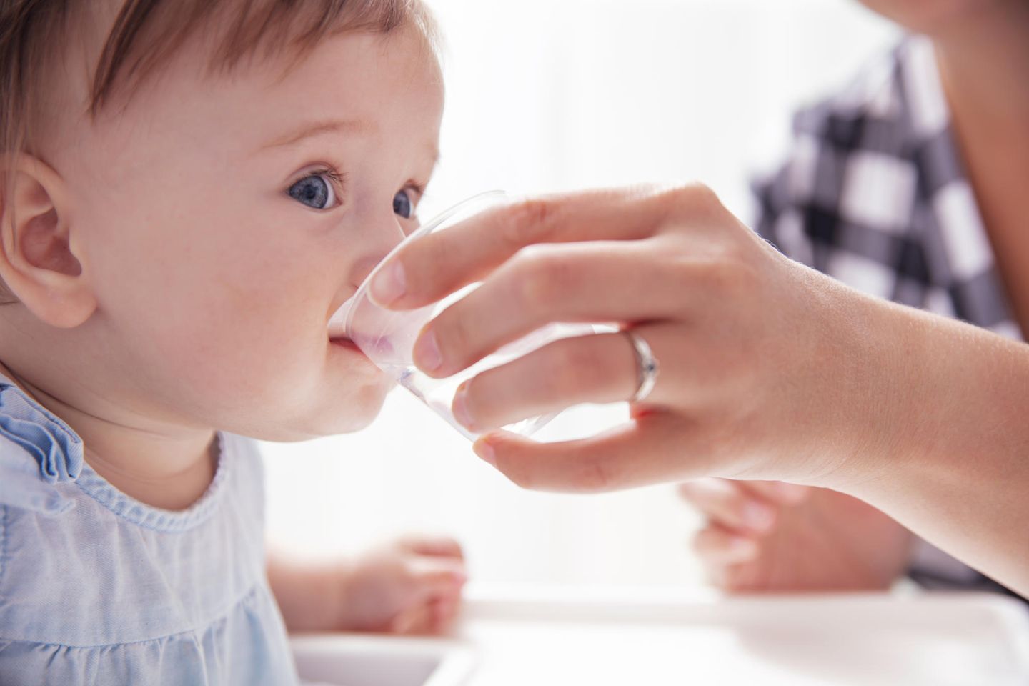 Niedliches Baby trinkt Wasser aus kleinem Becher