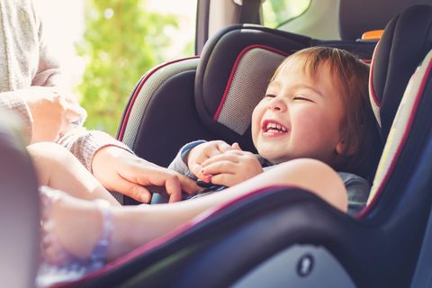 Reisebeschäftigung: Kleinkind sitzt lachend in einem Autositz