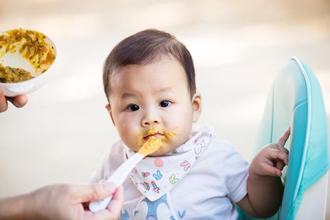 Asiatisches Baby bekommt Brei mit Ei gefüttert