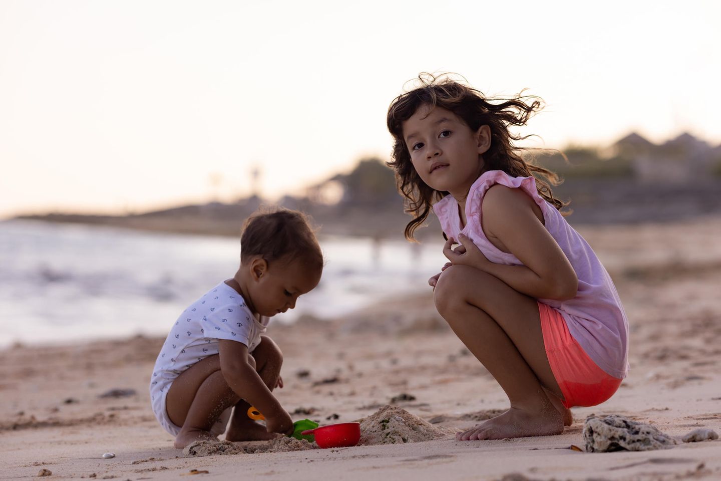Andere Länder, andere Sitten: Kind spielt mit Baby am Strand