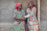 Andere Länder, andere Sitten: Ältere BiPoC Frau reicht anderer Frau die Hand