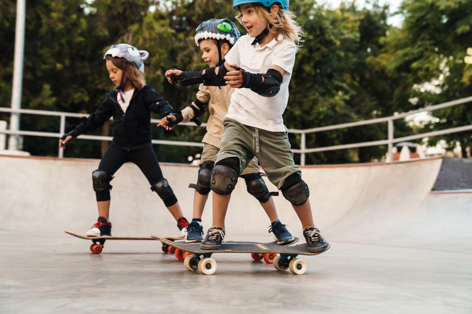 Kinder-Skateboards Test: Kinder fahren auf Skateboards durch einen Park
