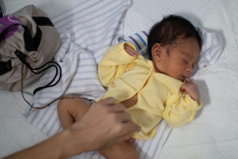 Baby in gelbem Jäckchen mit Plazentatasche