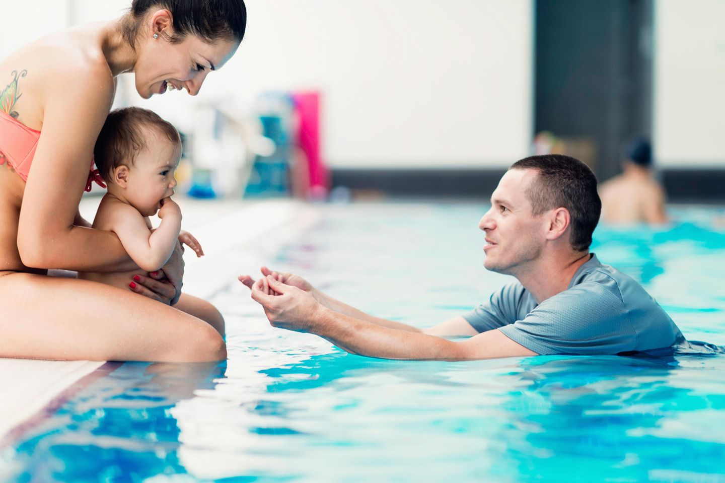 Babyschwimmen: Baby mit seinen Eltern am Beckenrand