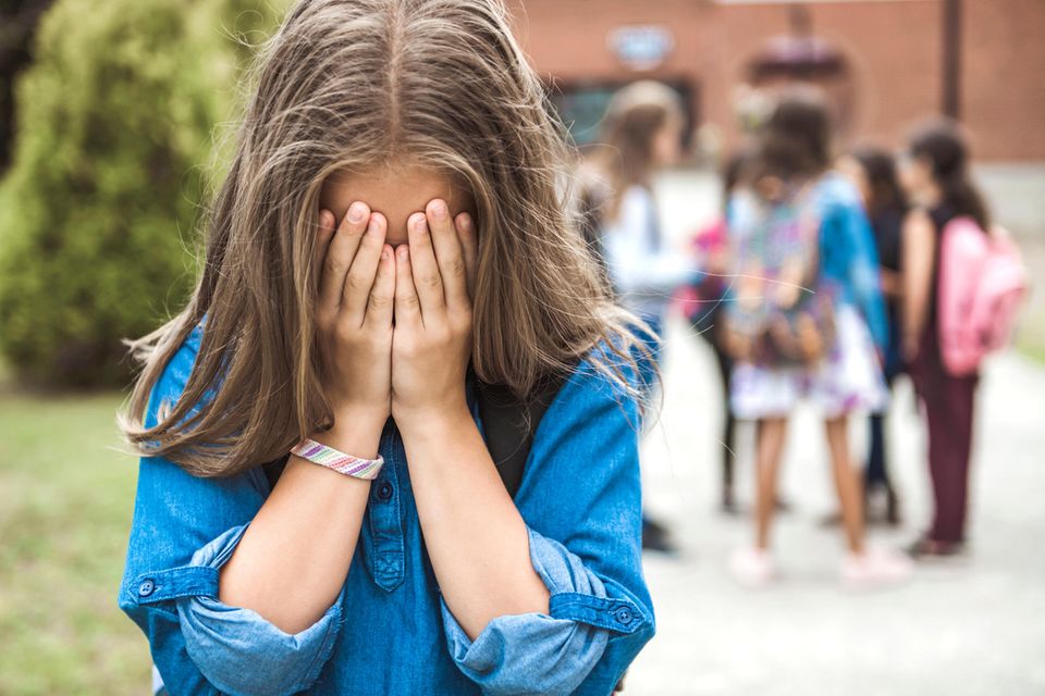 Mädchen ist verzweifelt auf dem Pausenhof einer Schule