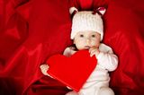 Babys lieben starke Farben: Baby hält rotes Herzchen