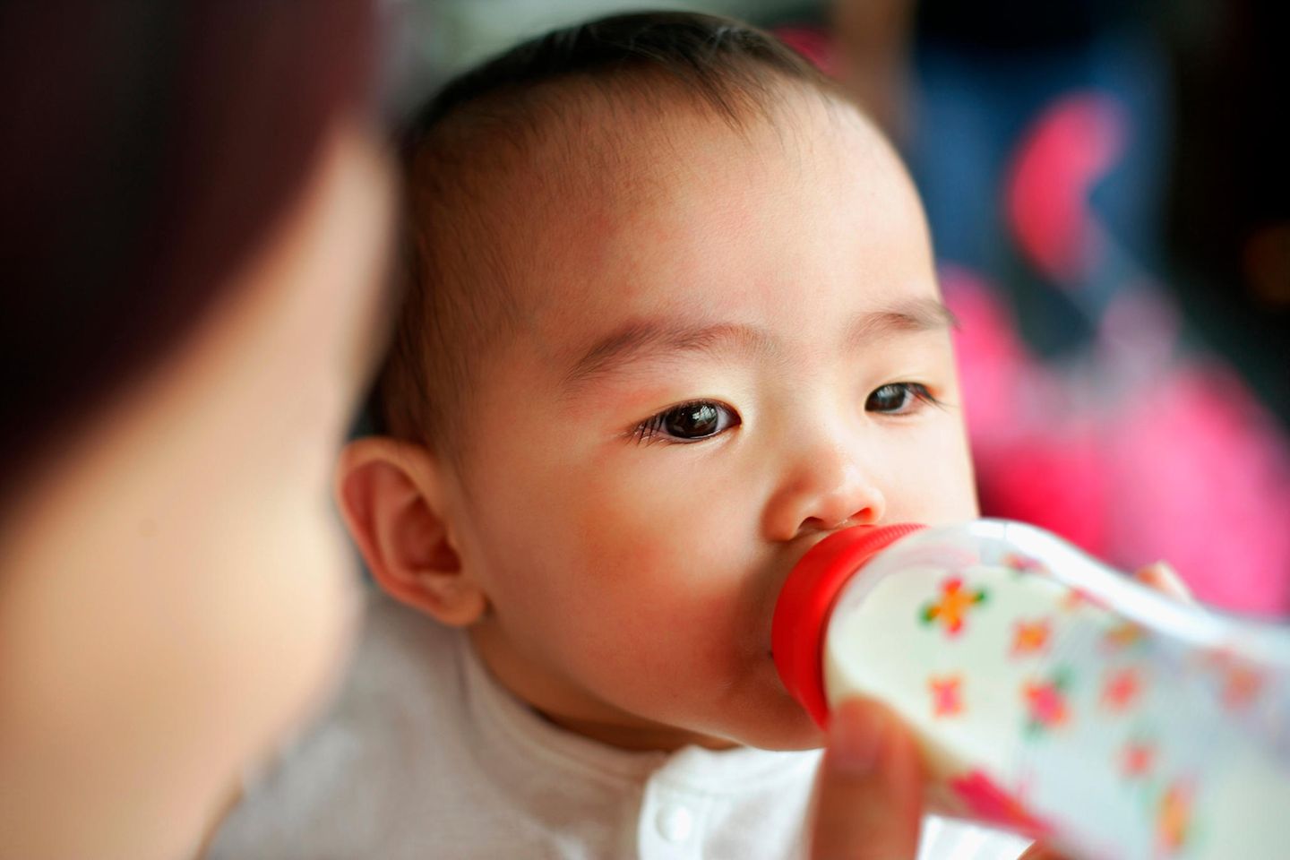 Asiatisches Baby trinkt aus dem Fläschchen