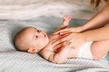 Liegendes Baby bekommt die Brust eingerieben