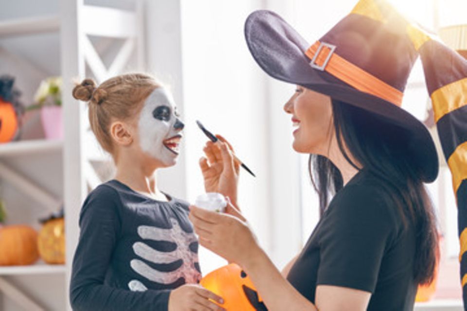 Halloween-Schminken für Kinder: Frau schminkt Kind als Skelett