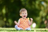 Baby sitzt auf Wiese