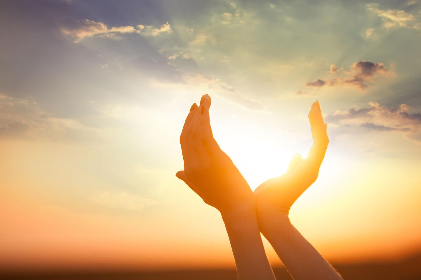 Sonnenzeichen: Frau streckt die Hände nach der untergehenden Sonne aus