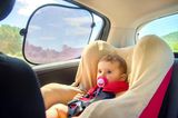 Entspannte Autofahrten mit Baby: Baby im Autositz mit Sonnenschutz am Fenster