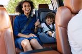Entspannte Autofahrten mit Baby: Beifahrerin sitzt mit dem Baby hinten