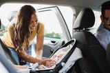 Entspannte Autofahrten mit Baby: Mutter gibt Baby Schnuller im Autositz