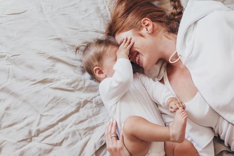 Blind mit Kind: Mutter liegt mit Baby auf dem Bett