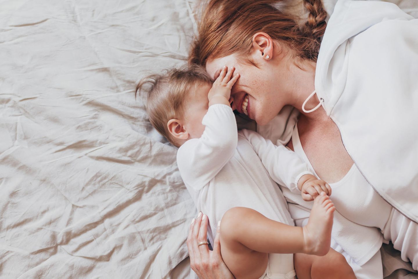 Blind mit Kind: Mutter liegt mit Baby auf dem Bett