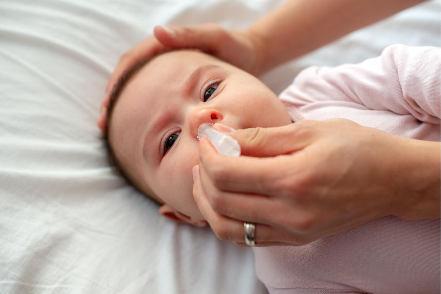 Nasentropfen für Babys: Baby bekommt aus einer Ampulle Tropfen in die Nase