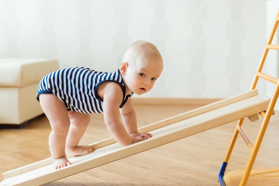 Baby Gym: Ein Baby krabbelt eine Holzschräge hinauf