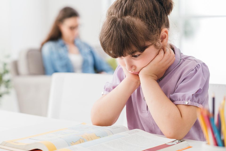 Leseschwäche: Mädchen schaut angestrengt auf ihr vor sich liegendes Buch